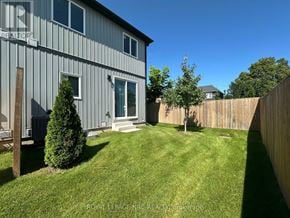 St. Catharines (Oakdale) townhouse for rent - A house with a grey exterior and a green lawn.