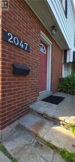 Burlington (Brant) apartment for rent - A red door with a black mailbox on a brick house with a number 2047 on the wall.