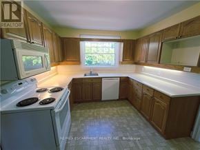 Burlington (Brant) apartment for rent - A kitchen with wooden cabinets and a white dishwasher.