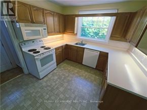 Burlington (Brant) apartment for rent - A kitchen with a white stove top oven and microwave, a white dishwasher, and wooden cabinets.