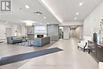 Hamilton (Durand) condo for rent - A spacious living room with a grey sofa and a television.