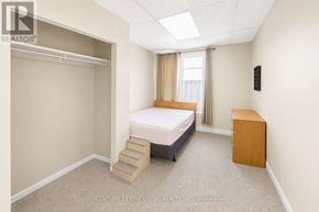 Barrie (City Centre) apartment for rent - A bedroom with a bed, dresser, and a window with curtains.