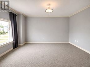 Barrie (City Centre) apartment for rent - A well-lit, empty room with grey carpeting and a window with curtains.