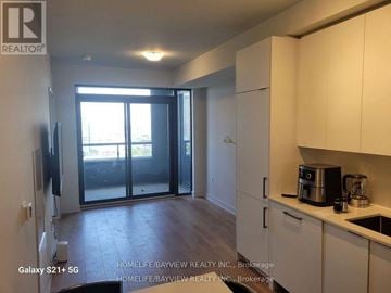 Vaughan (Concord) condo for rent - A kitchen with white cabinets and a black fridge.