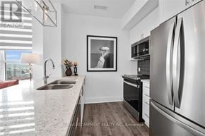 Hamilton (Waterdown) condo for rent - A modern kitchen with stainless steel appliances and a framed black and white picture on the wall.