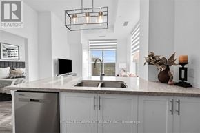 Hamilton (Waterdown) condo for rent - A modern kitchen with a large island and a woman washing dishes.