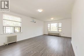 Toronto (Oakridge) multi-family for rent - A spacious room with wood flooring and two windows.
