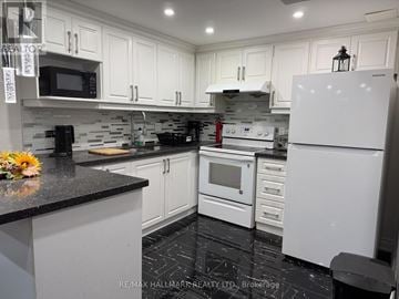 Vaughan (Maple) apartment for rent - A kitchen with white cabinets and black countertops.