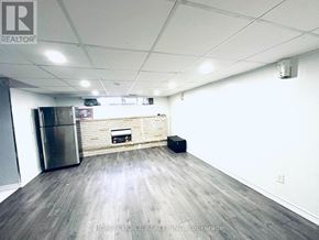 Brampton (Southgate) apartment for rent - A spacious room with a wooden floor, a stainless steel refrigerator, and a fireplace.