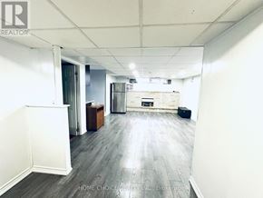 Brampton (Southgate) apartment for rent - A spacious room with wooden flooring and white walls, featuring a kitchenette with a refrigerator, oven, and sink.