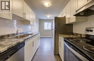 London apartment for rent - A kitchen with white cabinets and a black stove top.
