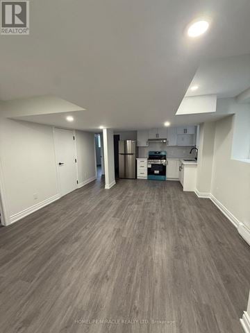 Barrie apartment for rent - A spacious room with a kitchen area in the background.
