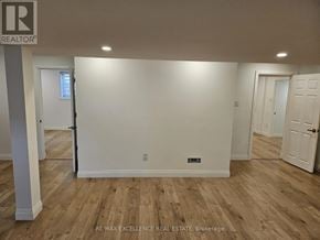 Kitchener apartment for rent - A room with wooden flooring and white walls, with a door on the left and a door on the right.