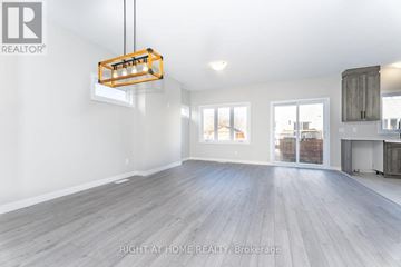 The Nation townhouse for rent - A spacious room with wooden flooring and a hanging light fixture.
