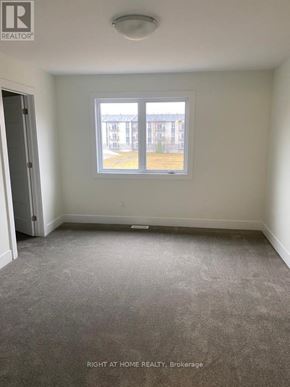 The Nation townhouse for rent - A room with a carpeted floor and a window showing a view of a building outside.