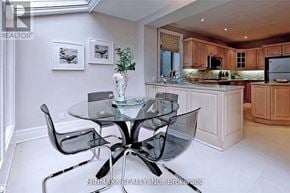 Toronto (Rosedale-Moore Park) apartment for rent - A glass dining table with four chairs is in the foreground of a well-lit kitchen.