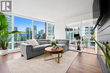 Vancouver apartment for rent - A living room with a grey couch and a coffee table in front of a large window.