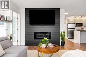 Vancouver apartment for rent - A living room with a grey couch, a coffee table, a fireplace, and a television mounted on the wall.