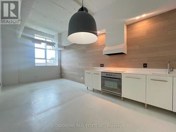 Toronto (Church-Yonge Corridor) condo for rent - A modern kitchen with white cabinets and a wooden accent wall.