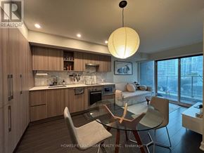 Toronto (Waterfront Communities) condo for rent - A modern kitchen with wooden cabinets and a glass table.