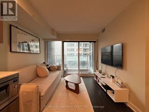 Toronto (Waterfront Communities) condo for rent - A living room with a white couch and a flat screen TV mounted on the wall.