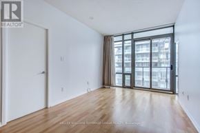 Toronto (Bay Street Corridor) condo for rent - A spacious room with wooden flooring and a large window with a view of a building outside.