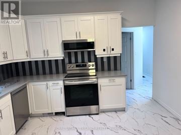London South (South E) triplex for rent - A kitchen with white cabinets and a black and white striped backsplash.