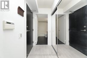 Toronto (Niagara) condo for rent - A hallway with a black wall on the right and a white door on the left.