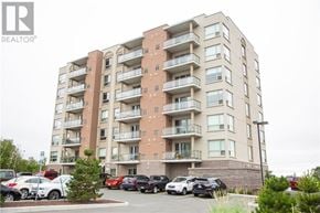 Greater Sudbury apartment for rent - A large apartment building with a parking lot in front.