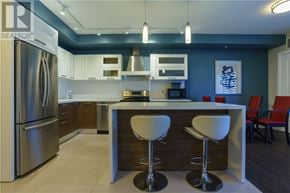 Greater Sudbury apartment for rent - A modern kitchen with a refrigerator, bar stools, and a counter.