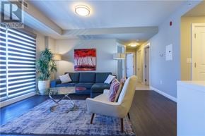 Greater Sudbury apartment for rent - A living room with a blue couch, a glass table, a white armchair, and a painting on the wall.