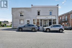 Smiths Falls apartment for rent - Two cars are parked in front of a building with a sign that reads "REMAX AFFILIATES MARQUIS Brokerage.".