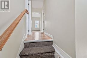 Smiths Falls apartment for rent - A hallway with a wooden staircase leading to a landing with a door.