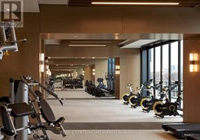 Toronto (North St. James Town) condo for rent - A gym with a row of exercise bikes and a row of dumbbells.