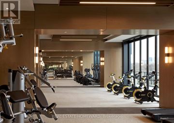 Toronto (North St. James Town) condo for rent - A gym with a row of exercise bikes and a row of dumbbells.