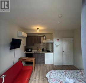 Toronto (Moss Park) apartment for rent - A small room with a red couch and a bed with a floral bedspread.