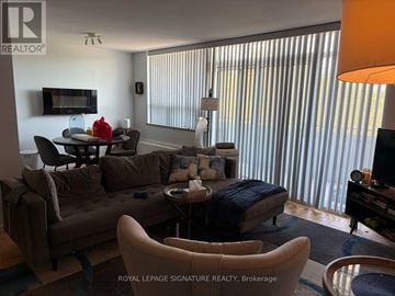 Toronto (Parkwoods-Donalda) condo for rent - A living room with a brown couch and a television.