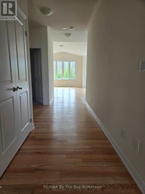 Wasaga Beach apartment for rent - A long hallway with wood floors and white walls.