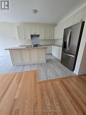 Wasaga Beach apartment for rent - A kitchen with white cabinets and a stainless steel refrigerator.