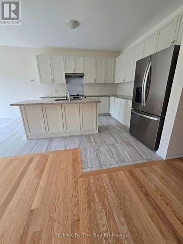 Wasaga Beach apartment for rent - A kitchen with white cabinets and a stainless steel refrigerator.