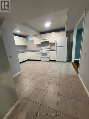 Bradford West Gwillimbury (Bradford) apartment for rent - A kitchen with white appliances and cabinets in a room with tiled flooring.