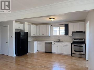 Bradford West Gwillimbury (Bradford) apartment for rent - A kitchen with white cabinets and a black fridge.