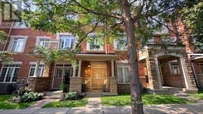 Oakville (Go Glenorchy) townhouse for rent - A tree stands in front of a house with a brown door.