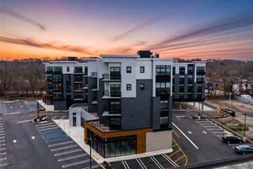 Paramus apartment for rent - A modern building with a parking lot in front of it during sunset.