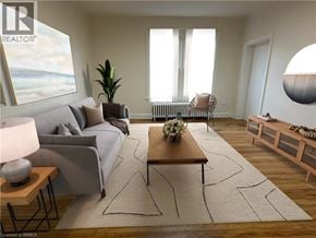 Brantford apartment for rent - A living room with a grey couch, a wooden coffee table, and a large window with white curtains.