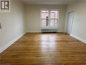 Brantford apartment for rent - A room with wooden flooring and a window with a white frame.