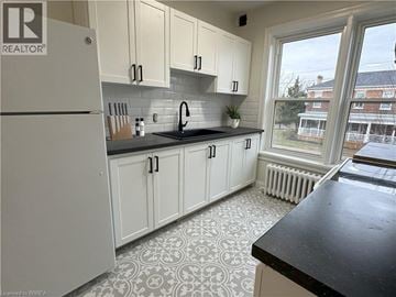 Brantford apartment for rent - A kitchen with white cabinets and a black countertop.