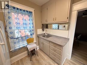 Brantford multi-family for rent - A kitchen with a sink, a window with a blue curtain, and a yellow chair.