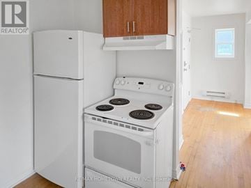 Brockville multi-family for rent - A white stove and refrigerator in a kitchen with wooden cabinets.