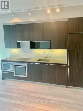 Toronto (Bayview Village) condo for rent - A modern kitchen with dark wood cabinets and stainless steel appliances.